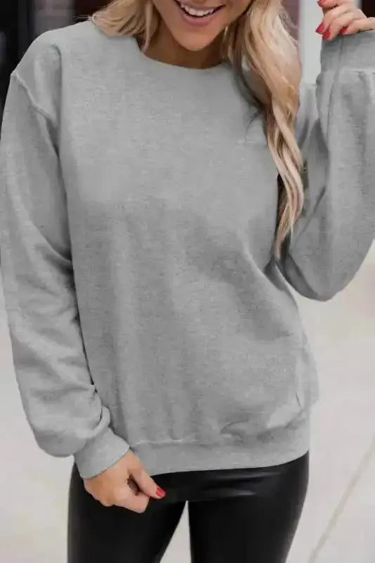 Gray classic crewneck sweatshirt styled with black leggings. A versatile and cozy top for winter layering.