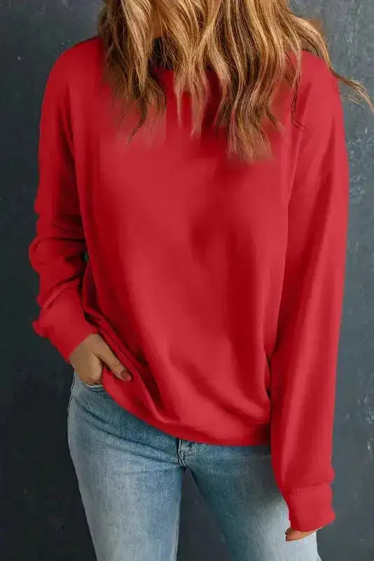 Red classic crewneck sweatshirt styled with jeans. Bold and cozy top for stylish winter outfits.