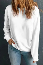 Classic crewneck sweatshirt in white, styled with light-wash jeans. Cozy and stylish essential winter wear for casual outfits.