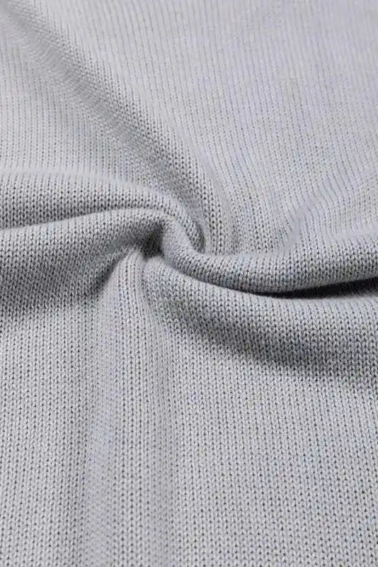 Twisted view of the grey knit fabric from Coffee Leopard Print Colorblock Pullover Sweater. Highlights the stretch and texture of the material.