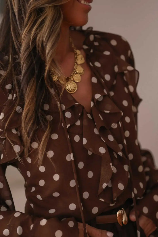 Close-up of coffee polka dot chiffon blouse showing tie neck and ruffled neckline. Feminine and elegant top for office or casual wear.