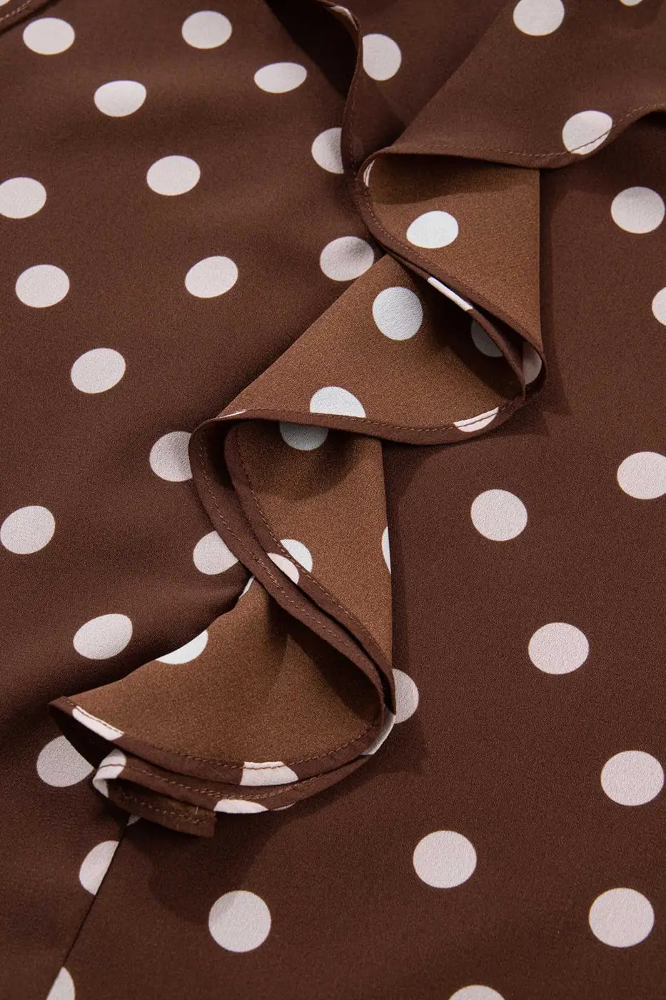 Zoomed-in view of the ruffled front design on the coffee polka dot chiffon blouse, highlighting the soft texture and elegant polka dot print.