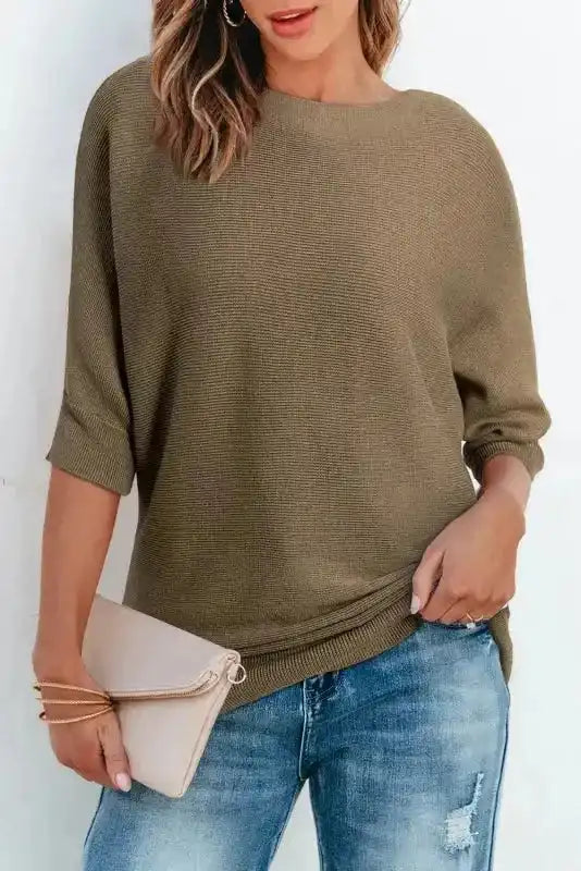 Loose-fit coffee ribbed knit jumper with half sleeves styled with blue jeans and a beige clutch, perfect for autumn layering.
