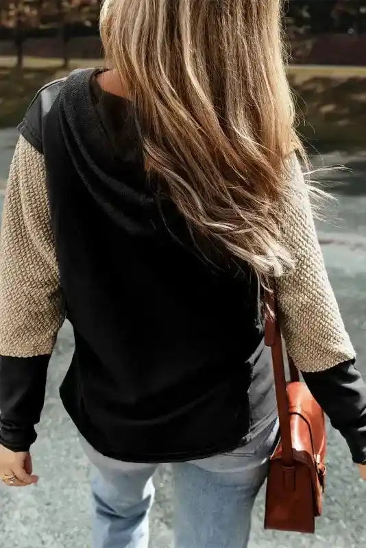 Back view of black Contrast Patchwork Hoodie with beige knit sleeves, stylish and relaxed for everyday wear.