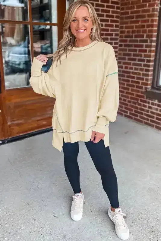 Front view of yellow baggy sweatshirt with multicolor stitching and drop shoulders, paired with leggings for a cozy autumn outfit.