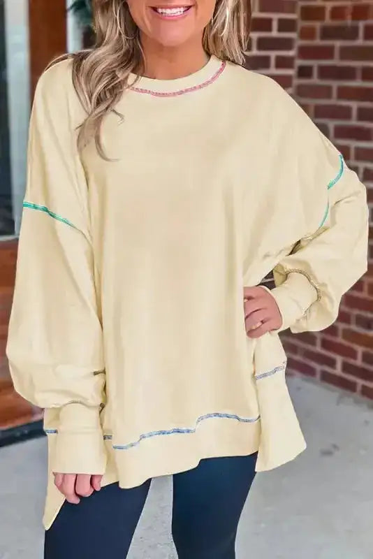 Yellow contrast stitching baggy sweatshirt with split hem and oversized fit, styled with black leggings for casual fall fashion.
