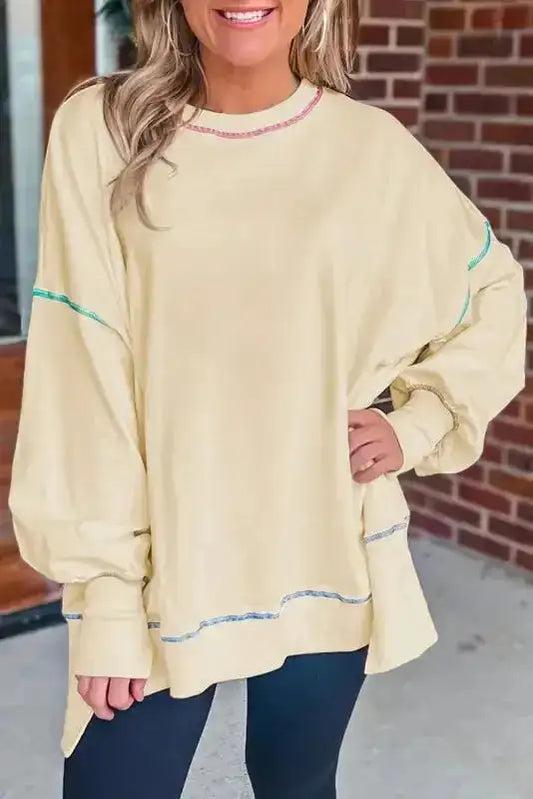 Yellow contrast stitching baggy sweatshirt with split hem and oversized fit, styled with black leggings for casual fall fashion.