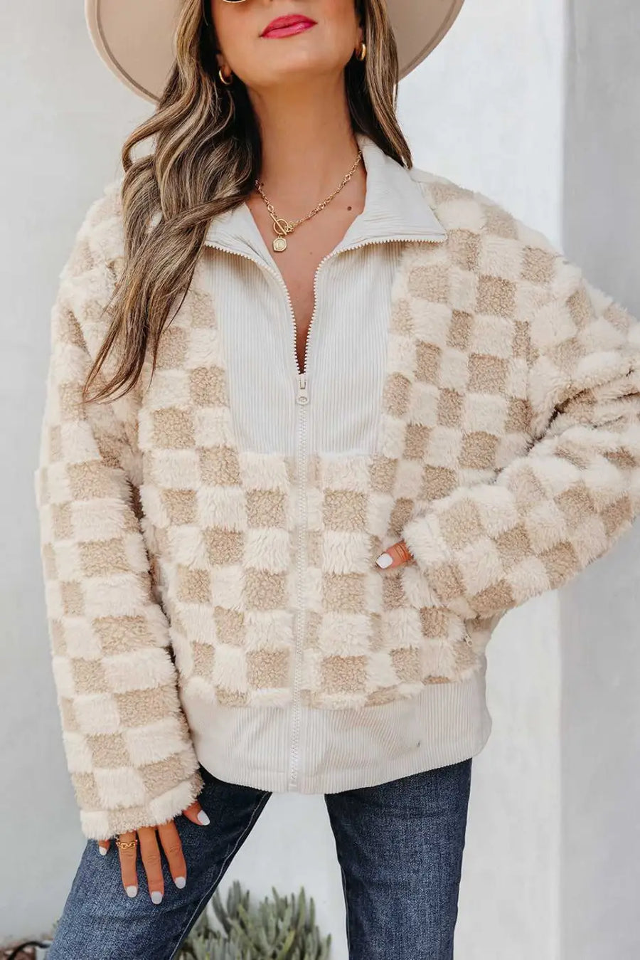 Person wearing a checkered beige and white jacket with a neutral background