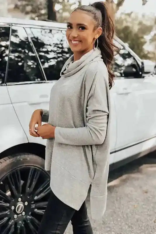 Side profile of the gray Cowl Neck Shift Tunic Top paired with black pants, offering a relaxed and fashionable winter outfit.