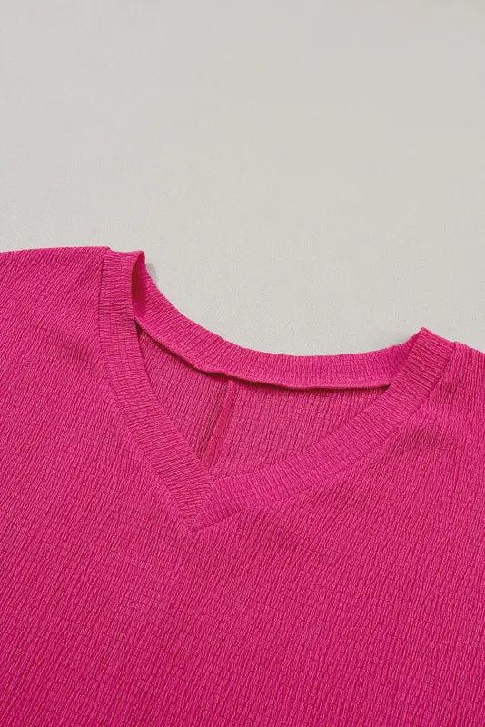 Bright pink v-neck sweater with textured knit pattern and crinkled v neck for a stylish look