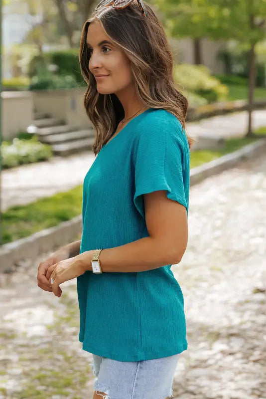 Teal short-sleeved top on a woman, featuring crinkled v neck design for a relax relax look