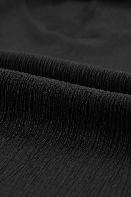 Detailed view of black crinkled fabric used in the V-neck T-shirt, showcasing its soft and textured finish.