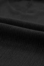 Detailed view of black crinkled fabric used in the V-neck T-shirt, showcasing its soft and textured finish.