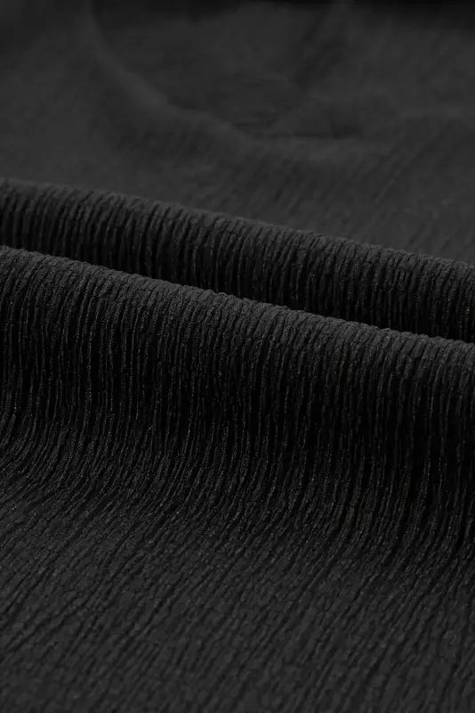 Textured black fabric with fine pleats on a crinkled v neck wide sleeve t-shirt. Relax relax