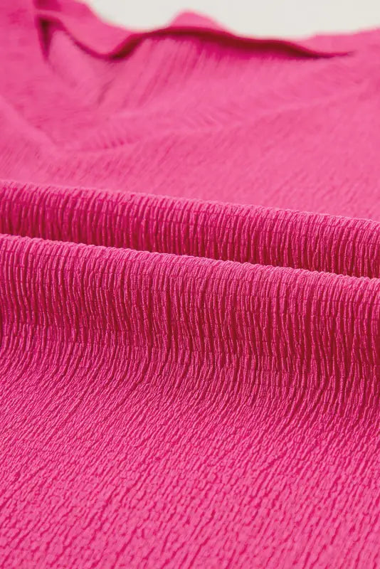 Vibrant pink fabric with fine textured pleats on black crinkled v neck wide sleeve t-shirt