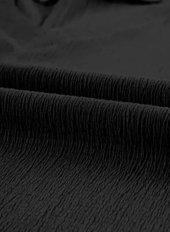 Close-up of black crinkled fabric texture, emphasizing the lightweight and airy material of the V-neck T-shirt.