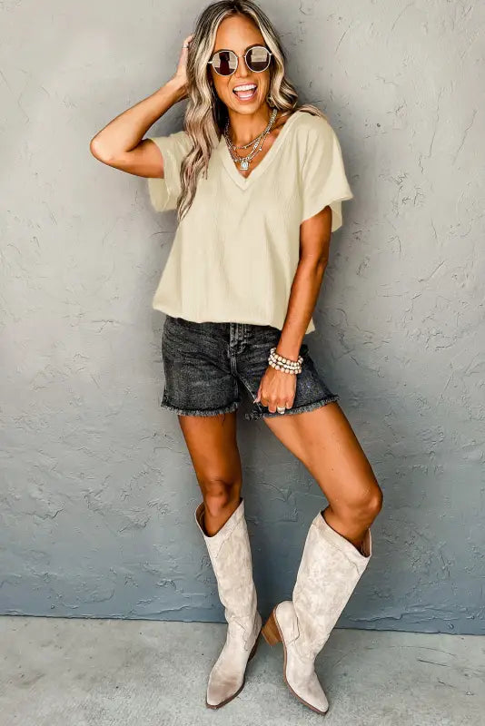 Smiling woman in casual black crinkled v neck wide sleeve t-shirt with sunglasses and cowboy boots