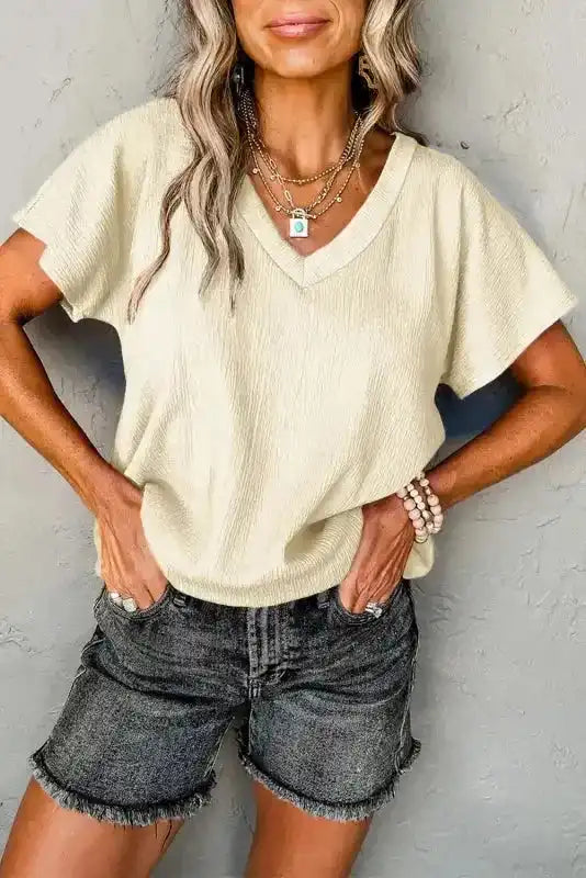 Crinkled V-Neck T-Shirt in cream color paired with denim shorts, offering a light and breezy summer style.