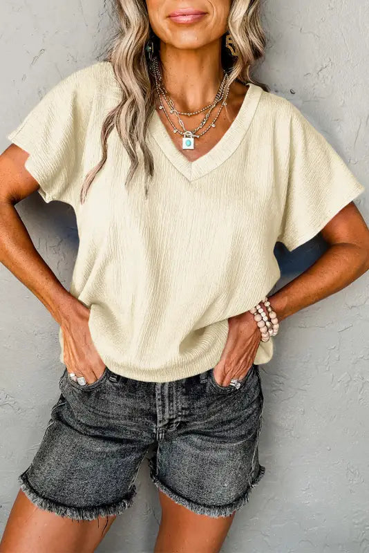 Cream v-neck sweater, denim shorts, and layered necklaces for a relax relax casual look