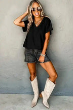 Model wearing black Crinkled V-Neck T-Shirt with denim shorts and boots, showcasing a chic casual style.
