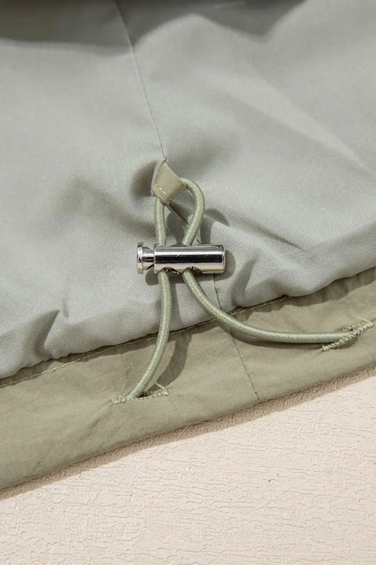 Interior drawstring toggle of Cropped Hooded Utility Jacket in laurel green, highlighting adjustable fit and casual utility style.