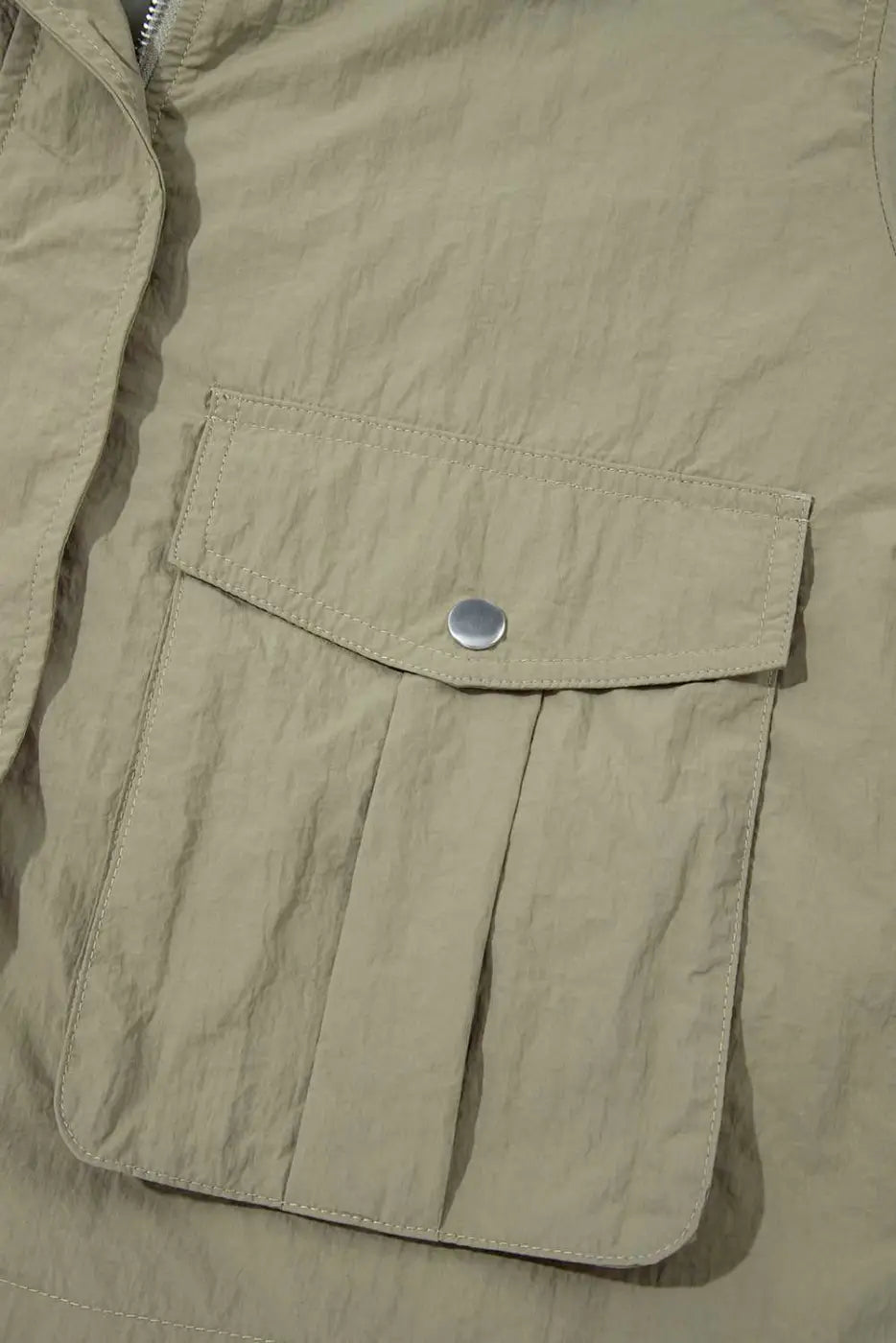 Front flap pocket with snap button on Cropped Hooded Utility Jacket, showcasing practical storage and solid color utility style.