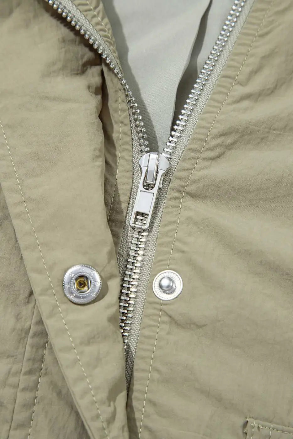 Detail of zipper and snap button closure on Cropped Hooded Utility Jacket, showcasing secure and stylish outerwear construction.