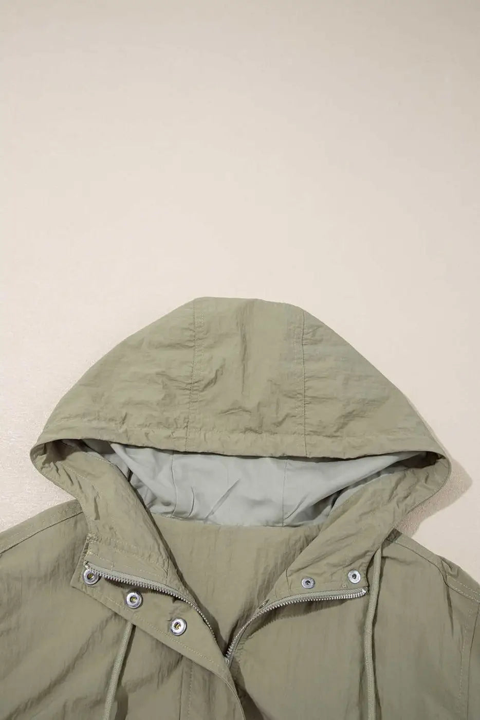 Close-up of adjustable hood on Cropped Hooded Utility Jacket in laurel green, emphasizing comfort and weather-ready design.