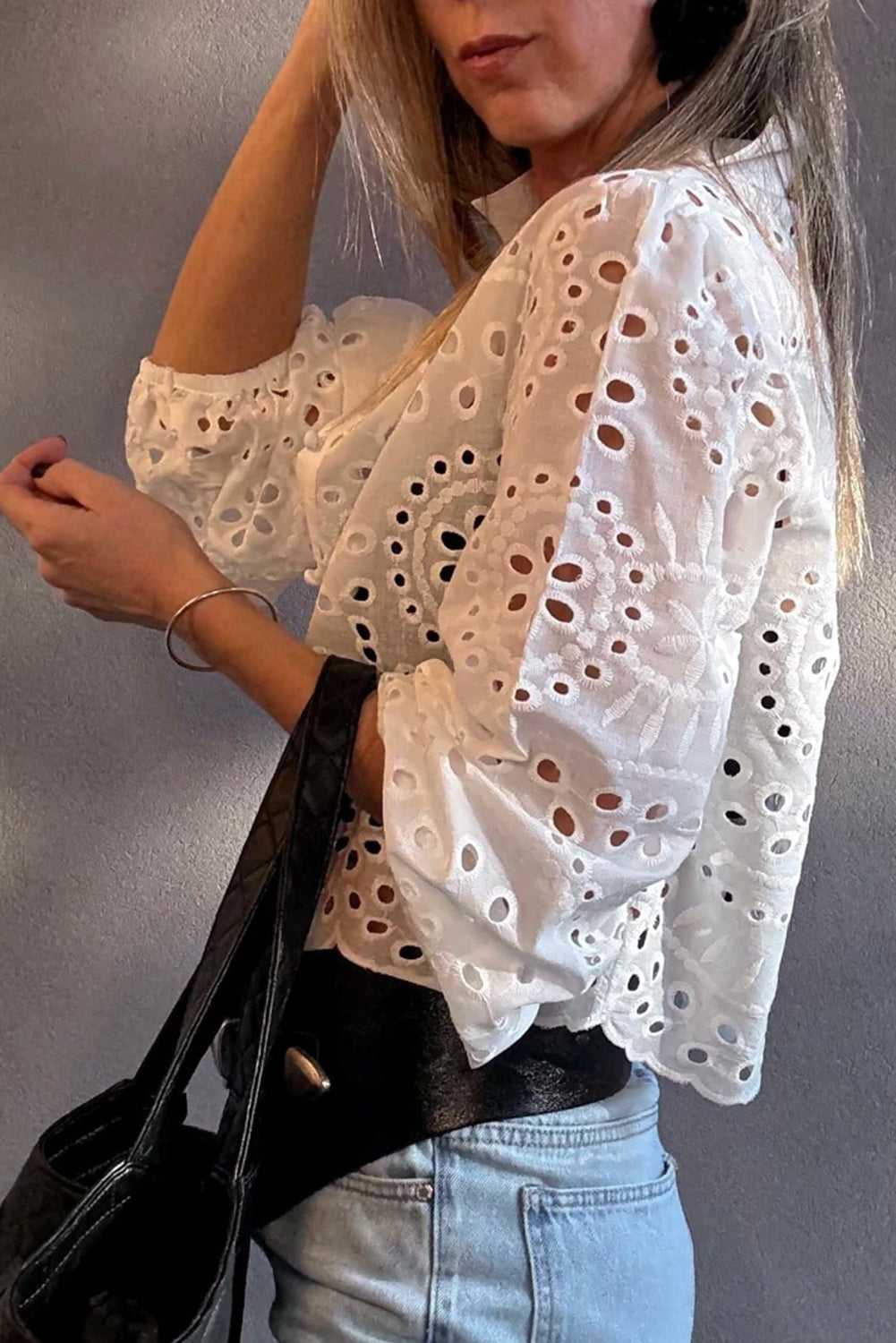 Woman wearing a White Cutwork Embroidered Crop Top with a black bag against a gray background
