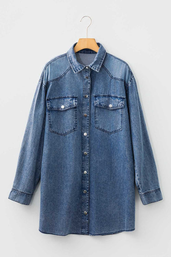 Flat lay of raw hem oversized denim shirt dress in medium blue with button front, long sleeves, and chest pockets, made from 100% cotton denim.