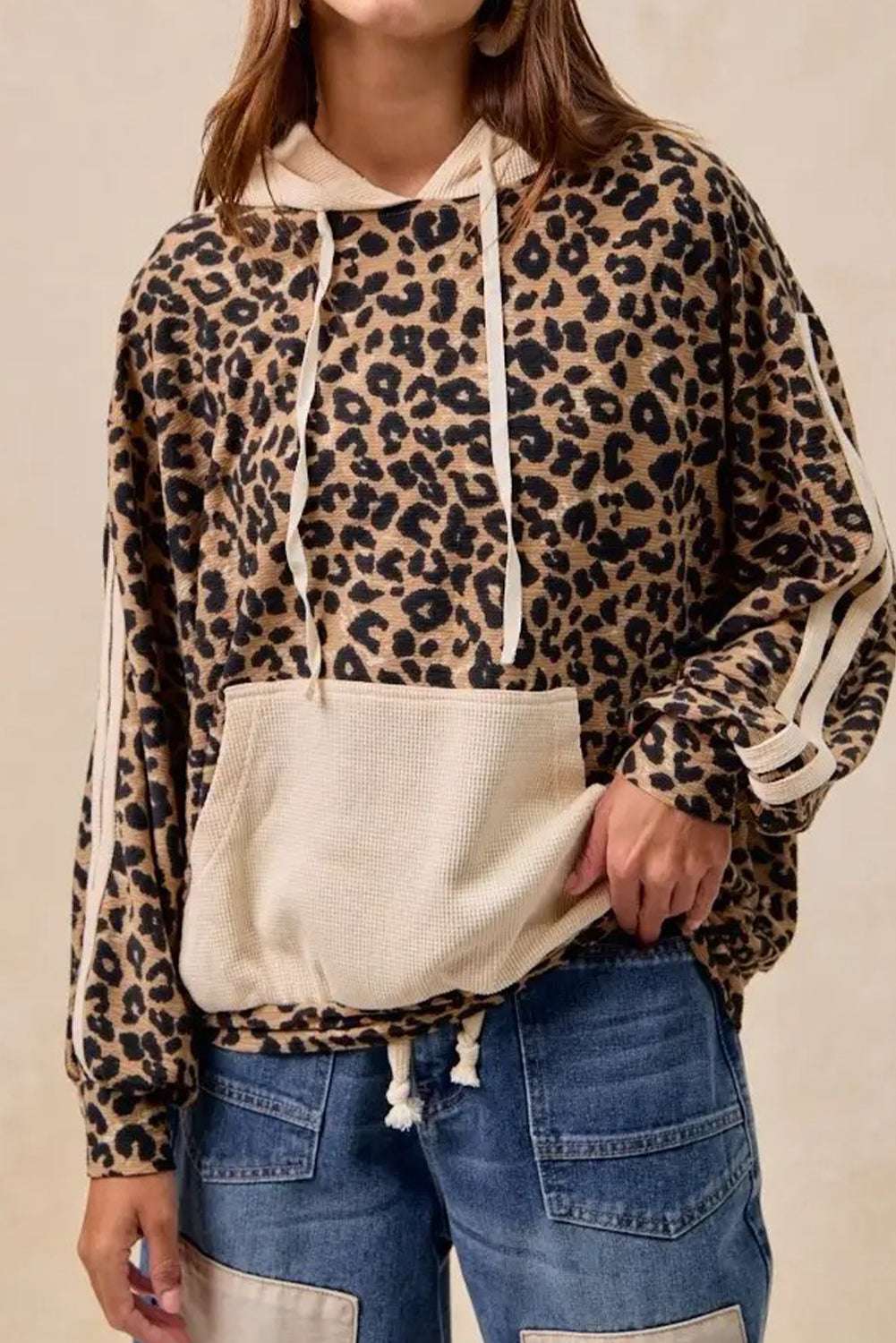 Ladies Leopard Print Waffle Knit Kangaroo Hoodie with beige drawstring hood and front pocket, styled with casual denim jeans.