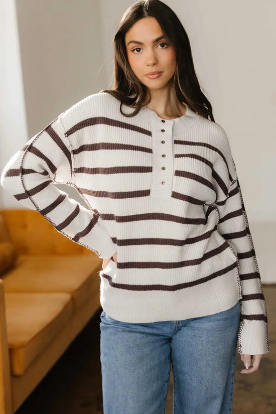 Model posing in casual slouchy striped Henley jumper, perfect for layering in fall with its soft knit and relaxed fit.