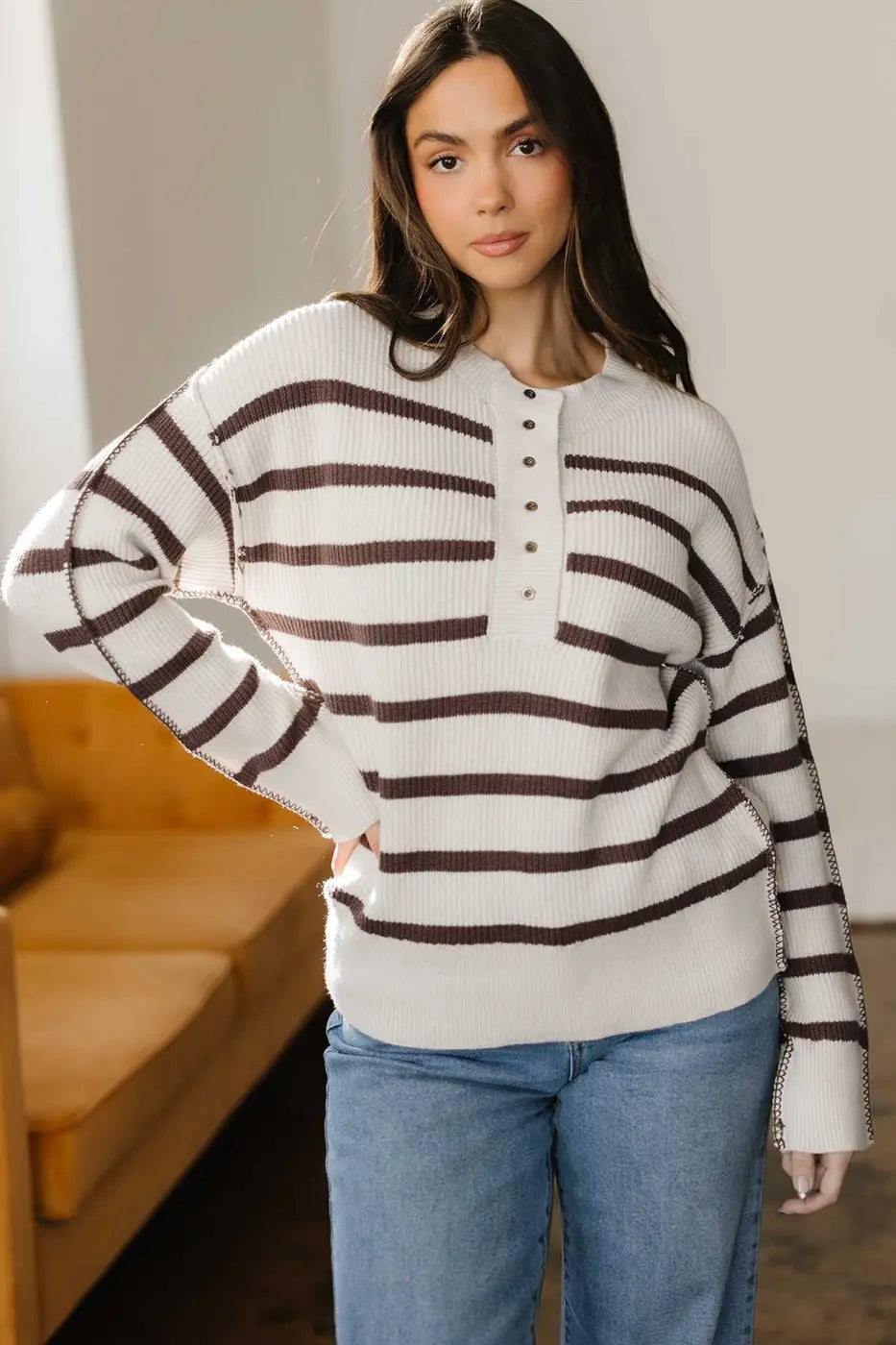 Model posing in casual slouchy striped Henley jumper, perfect for layering in fall with its soft knit and relaxed fit.