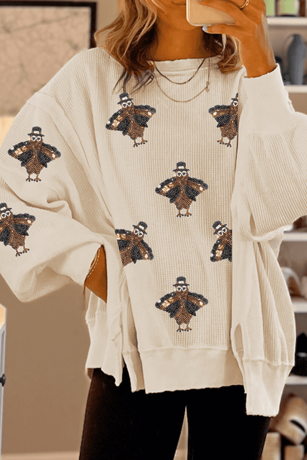 Beige sweater with turkey pattern worn by a person, blurred background