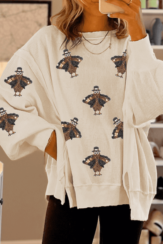 Beige sweater with turkey pattern worn by a person, blurred background