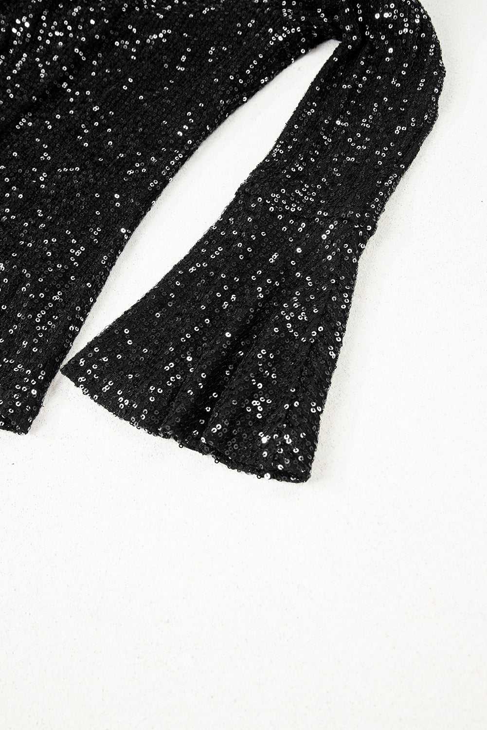 Bell sleeve detail of black sequin evening blouse, showcasing elegant flare and shimmering texture for night out looks.