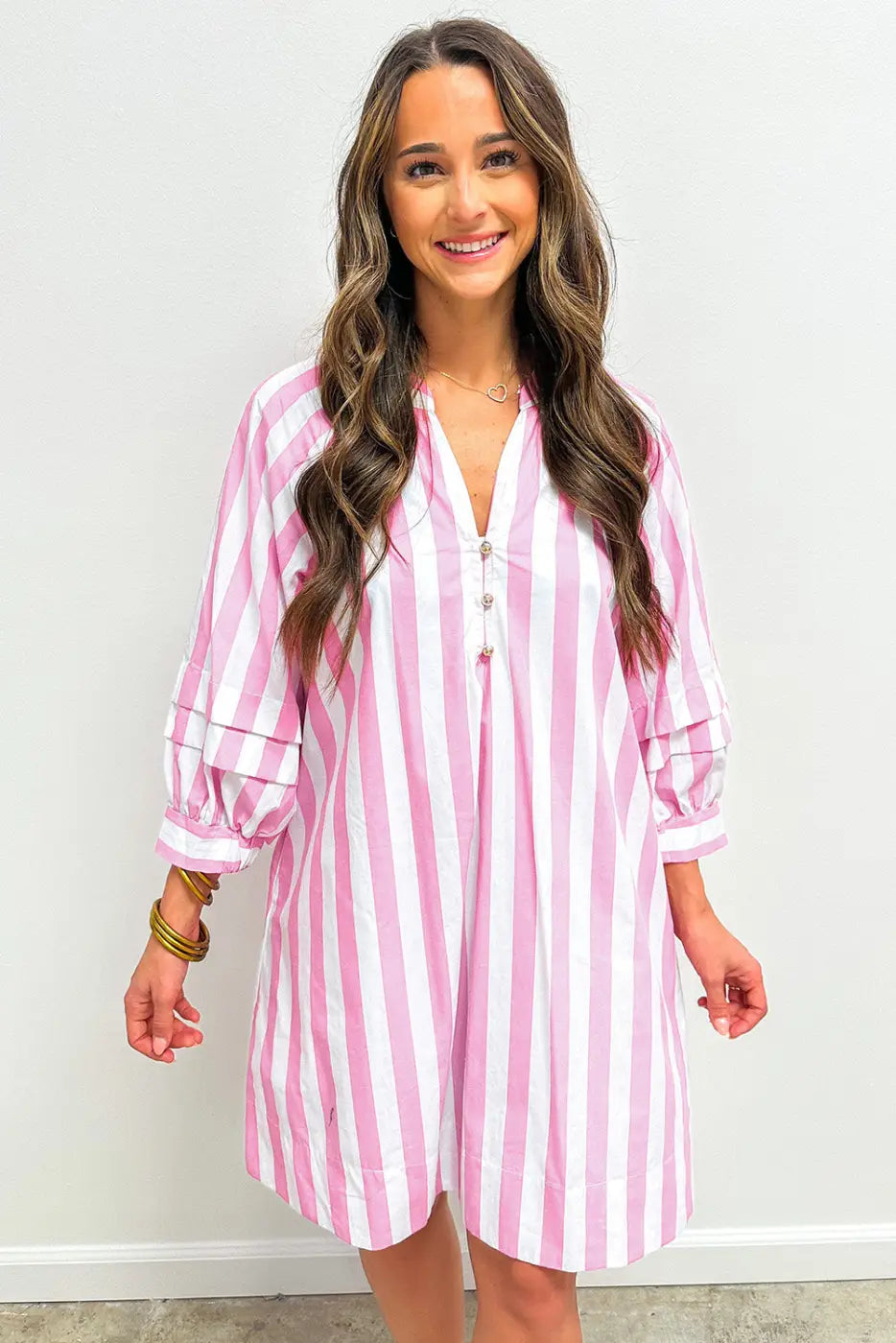 Woman wearing a pink and white striped dress against a plain background