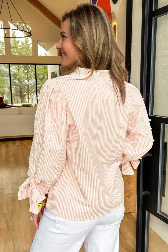 Back view of the Bow Cuff Pearl Embellished Blouse worn by model, featuring pearl-detailed sleeves and bow cuffs.