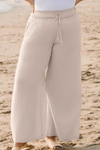 Wide Leg Plus Linen Pants in beige with elastic waistband and drawstring, styled for casual beachwear. Lightweight summer trousers by Fashionfitz.