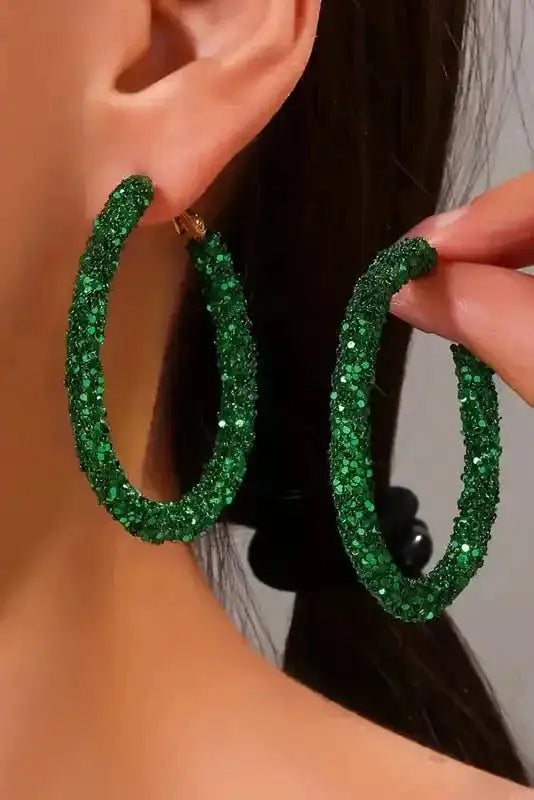 Close-up of St. Patrick's Sequin Loop Earrings - Dark Green by Fashionfitz being worn and held, highlighting bold glitter texture and hoop shape.