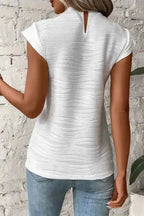 Back view of white textured cap sleeve mock neck top featuring a keyhole closure, paired with light blue jeans for daily wear.
