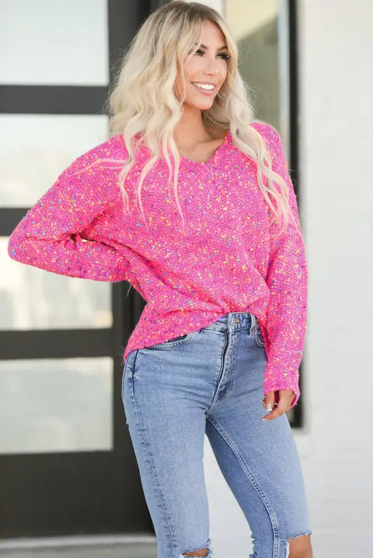 Woman relaxing in dark pink colorful spots v neck casual sweater and blue jeans