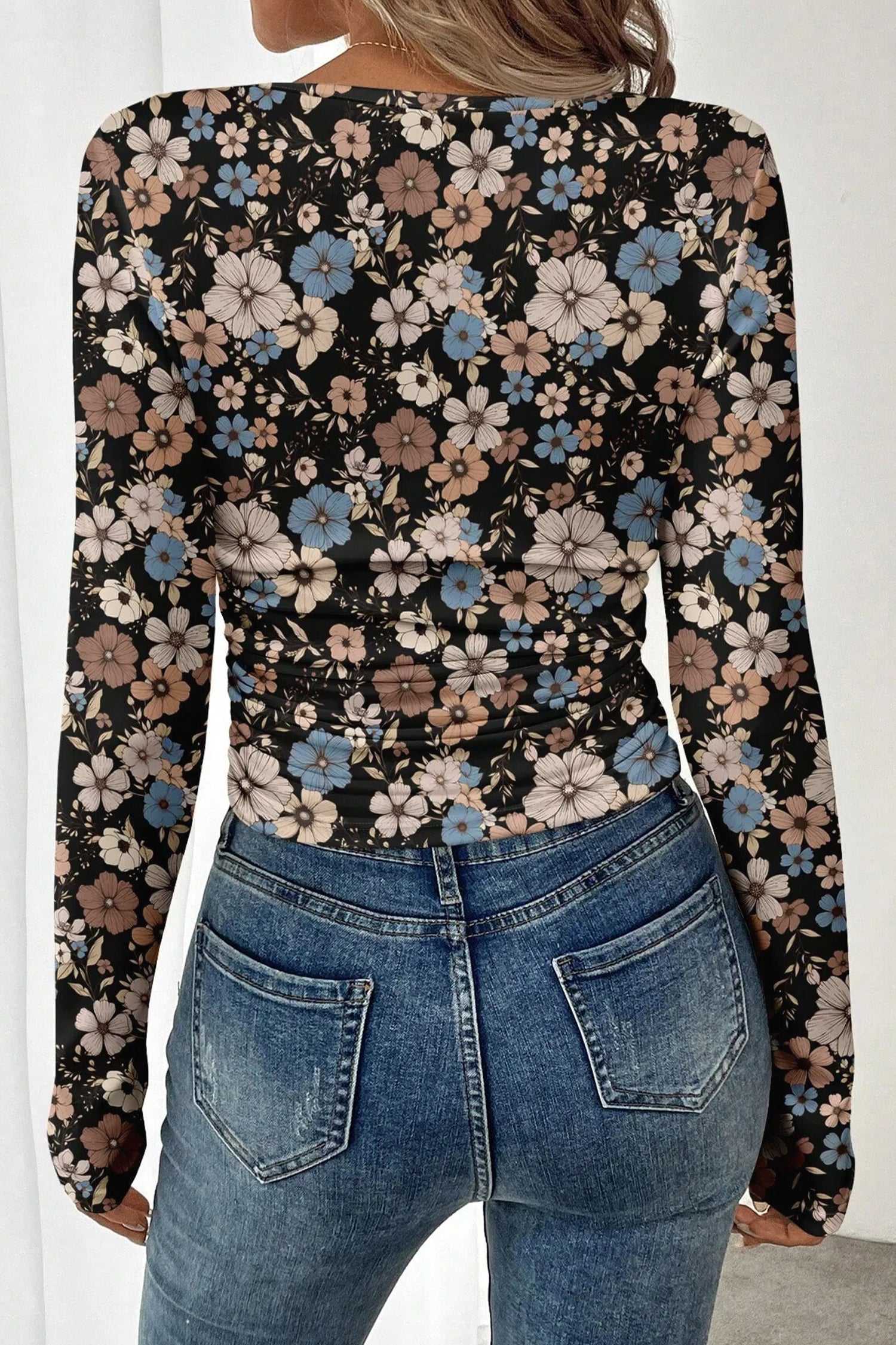 Back view of black floral slim long sleeve top showing all-over floral print and ruched waist for a flattering fit.