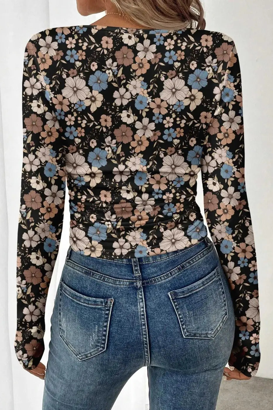 Back view of black floral slim long sleeve top showing all-over floral print and ruched waist for a flattering fit.