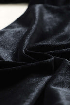 Close-up of soft black velvet fabric texture used in jogger trousers, emphasizing luxurious feel and high-quality material.
