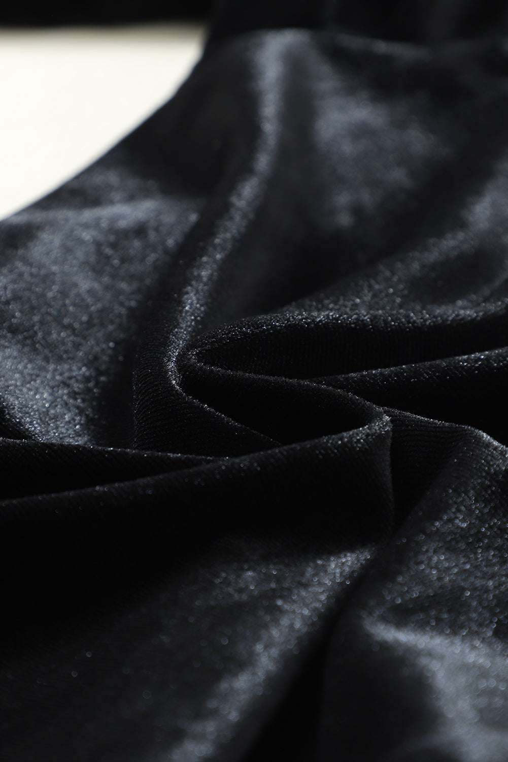 Close-up of soft black velvet fabric texture used in jogger trousers, emphasizing luxurious feel and high-quality material.