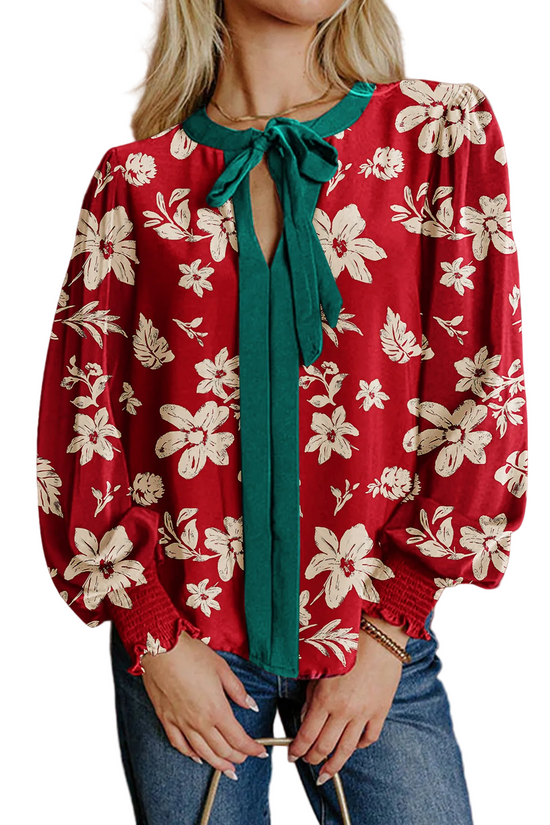 Red floral blouse with a green tie worn by a person against a brown background
