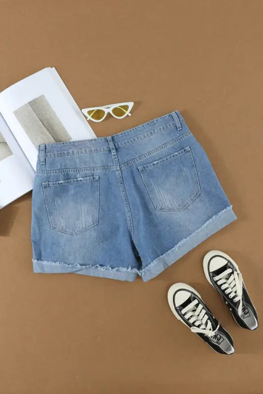 Distressed ripped denim shorts with rolled cuffs and visible pockets for a relaxed look