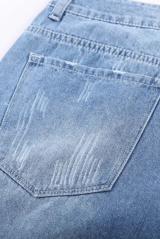 Back pocket of distressed ripped denim shorts with visible stitching and fading