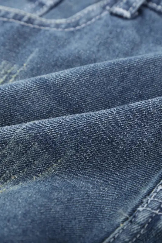 Close-up of textured weave and folds of distressed ripped denim shorts - rolled hem